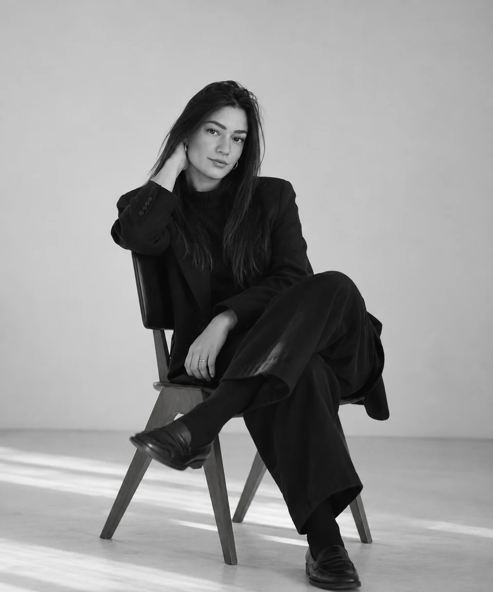Retrato em preto e branco de Carolina Oliveira, sentada, com conjunto preto